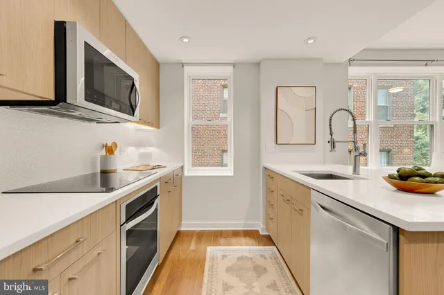 a kitchen with stainless steel appliances granite countertop a sink and a stove top oven with wooden floor