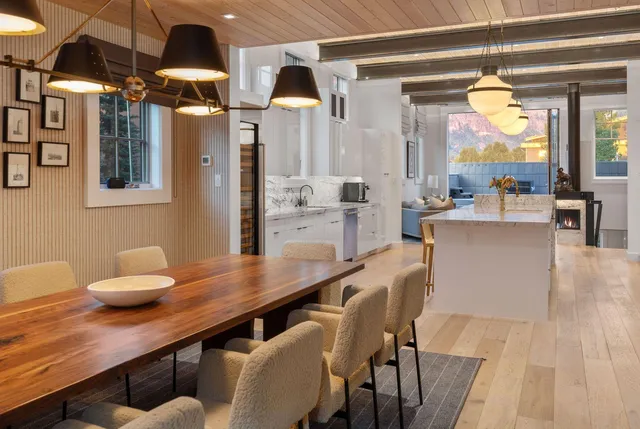 a dining hall with stainless steel appliances kitchen island granite countertop a table chairs and a wooden floor