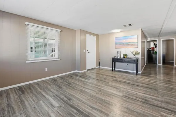 a view of an empty room with wooden floor and a window