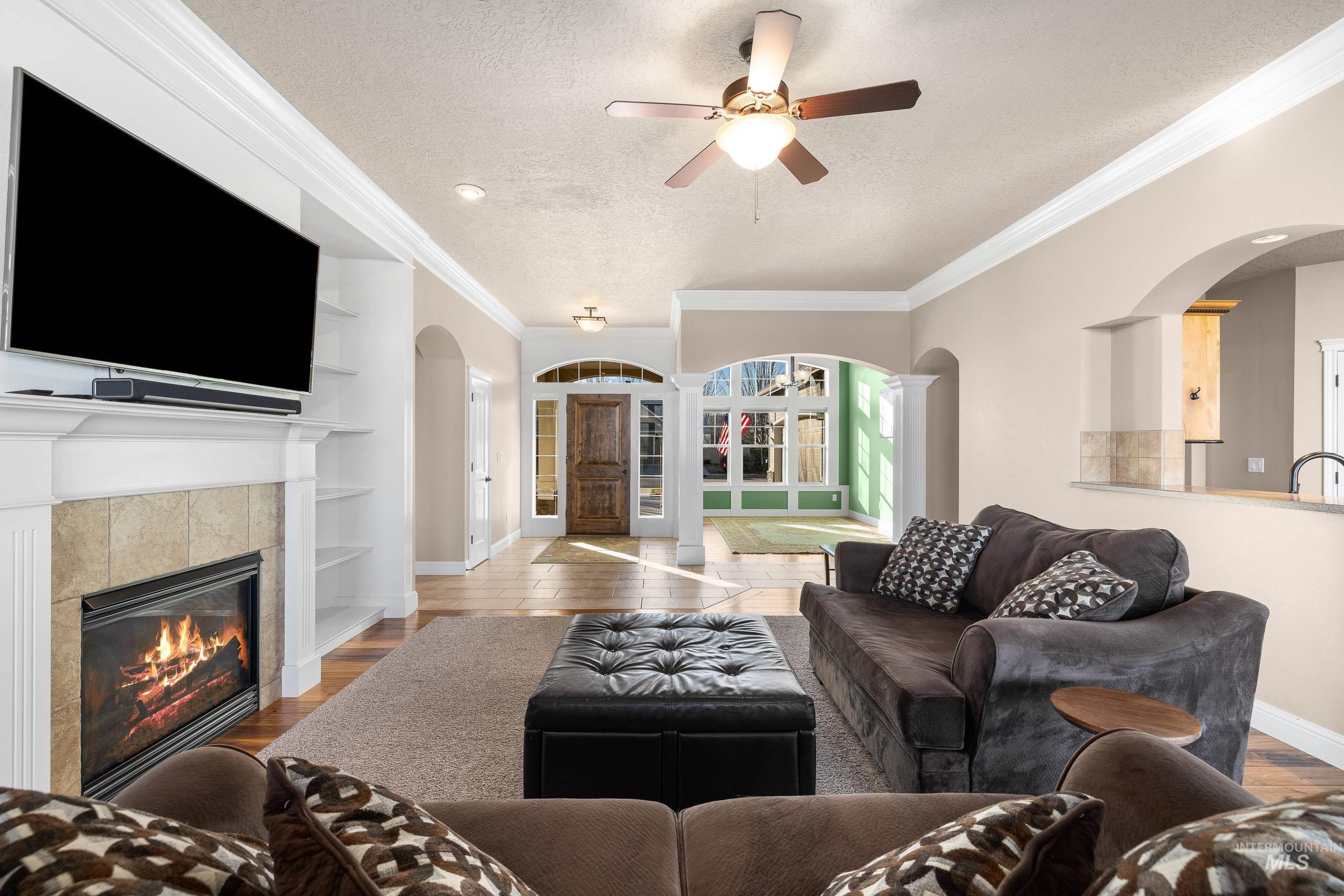 2208 East Sicily Street Meridian, ID 83642 - Photo 12 of 50 Living room with arched walkways, a textured ceiling, ornamental molding, built in shelves, and wood finished floors