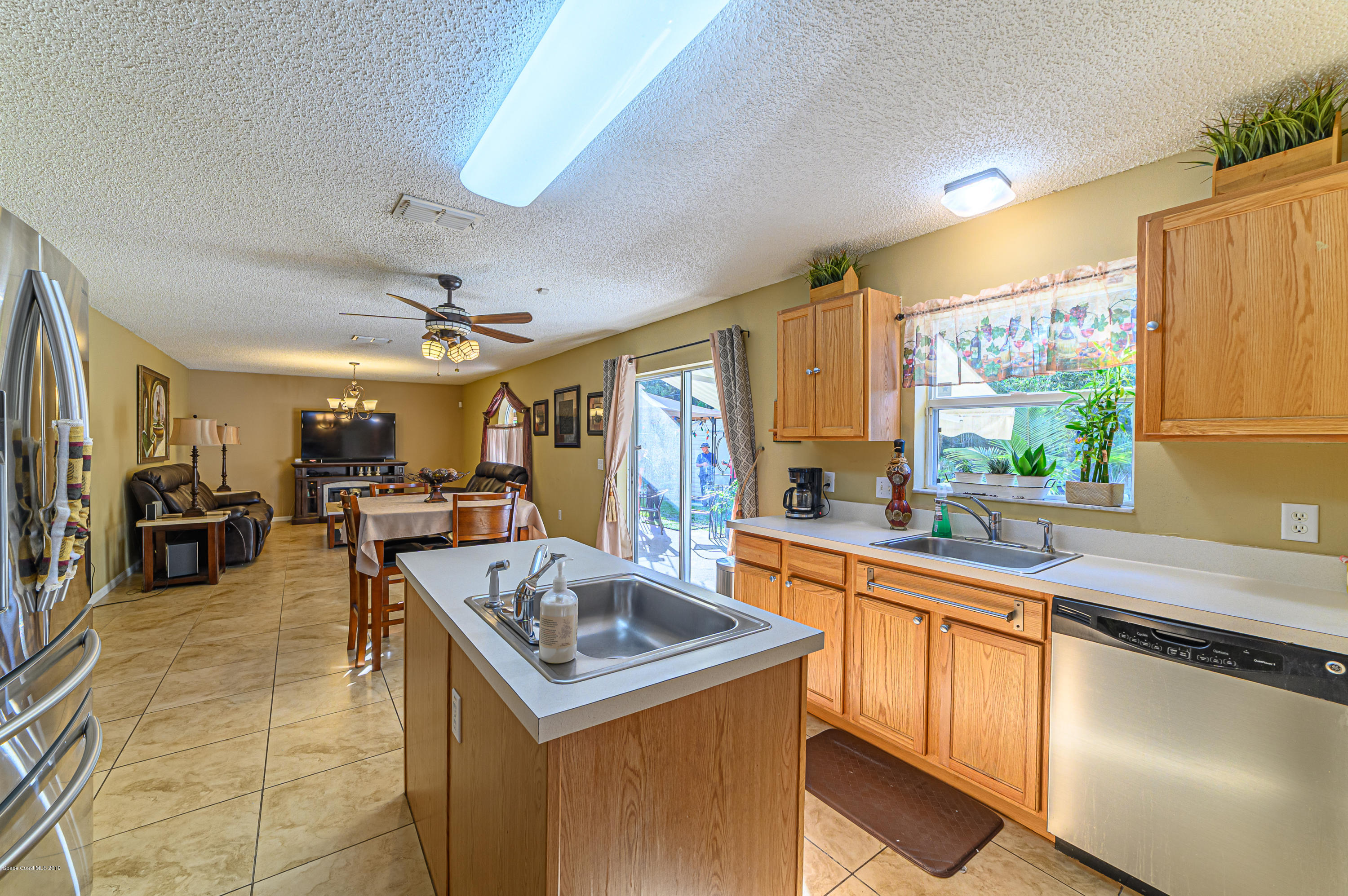 1393 Rabbit Street Southeast Palm Bay, FL 32909 - Photo 22 of 47 a kitchen with a sink a counter top space stainless steel appliances cabinets and a large window