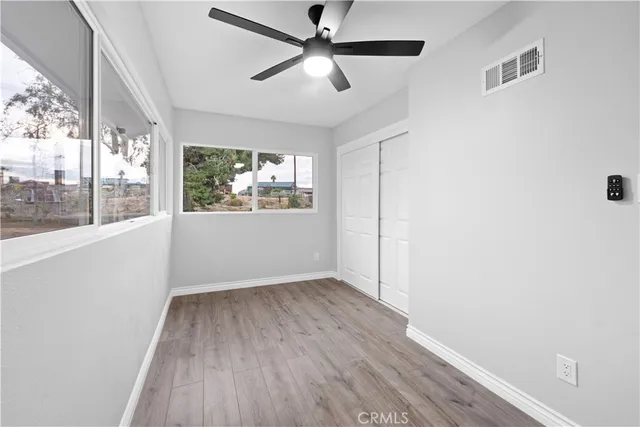 a view of empty room with wooden floor and fan