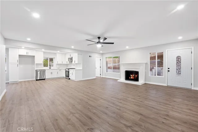 a view of kitchen and empty room with wooden floor and fireplace