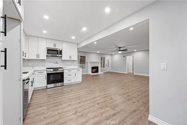 a open kitchen with granite countertop a stove top oven a sink dishwasher and a refrigerator with wooden floor