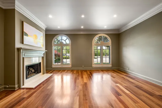 an empty room with wooden floor fireplace and windows