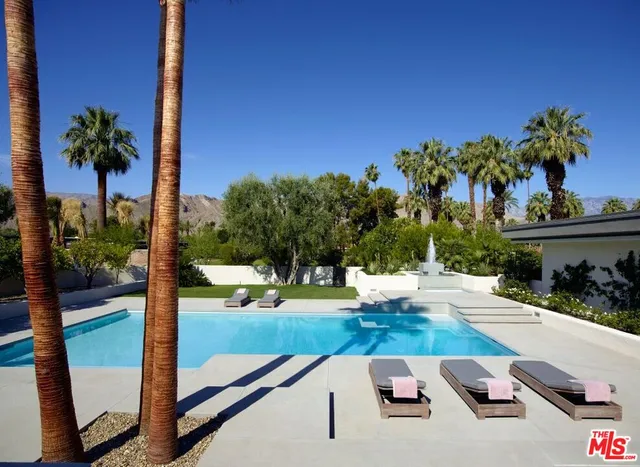 a view of backyard with swimming pool and seating space