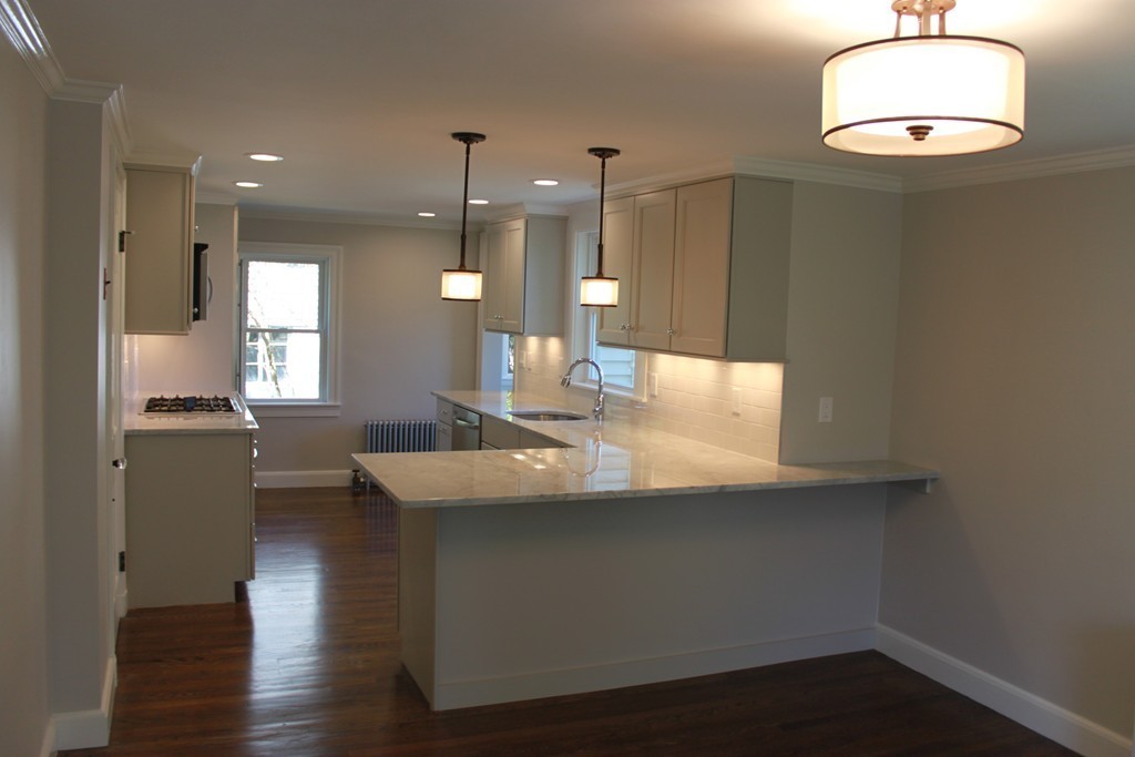 52 Roundwood Road Newton, MA 02464 - Photo 5 of 19 a kitchen with kitchen island stainless steel appliances a table chairs refrigerator and sink