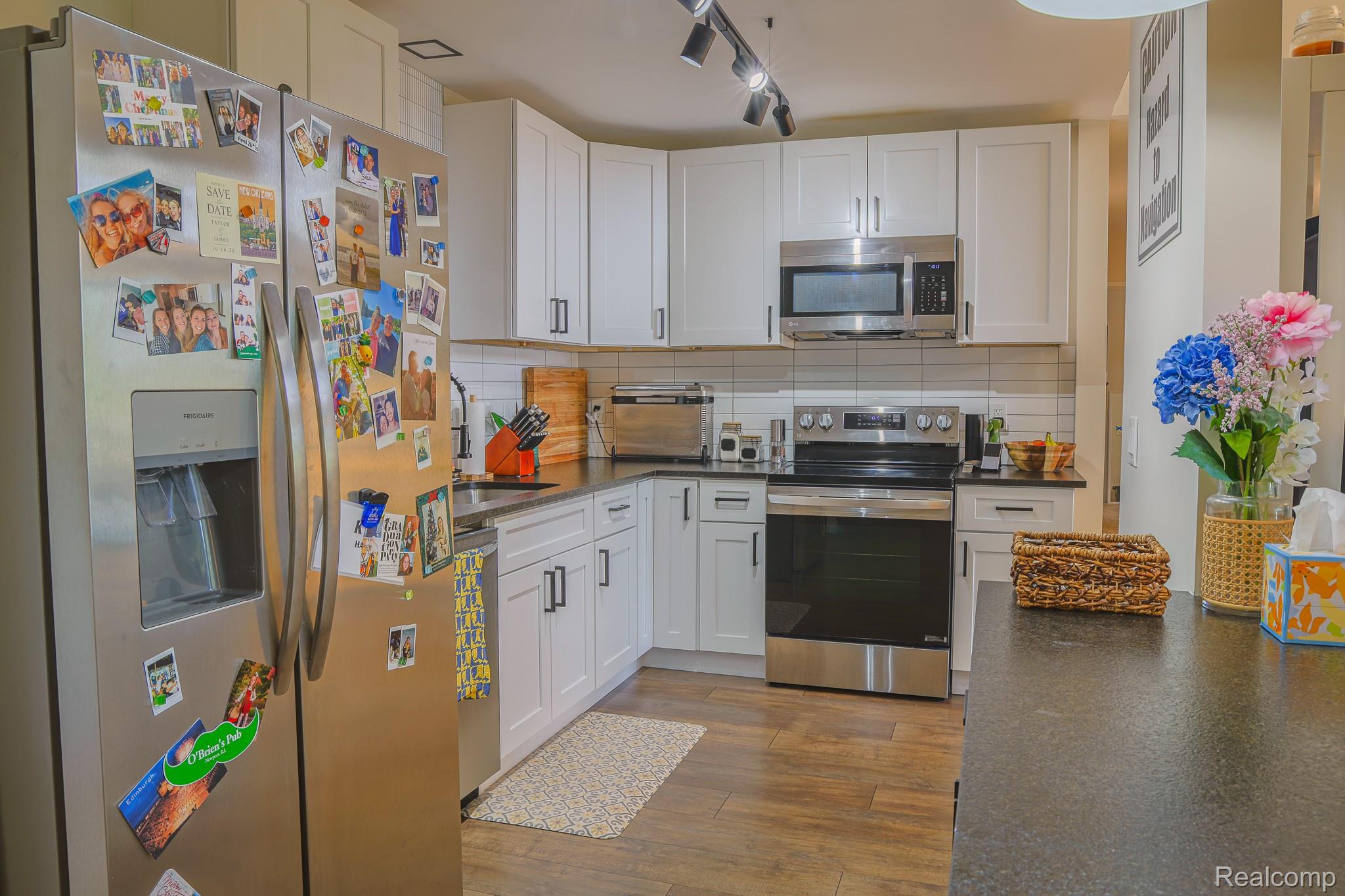 1989 Klingensmith Road, Unit 46 Bloomfield Hills, MI 48302 - Photo 5 of 41 Kitchen featuring white shaker-style cabinetry with dark hardware, stainless steel appliances, dark countertops, and a white subway tile backsplash