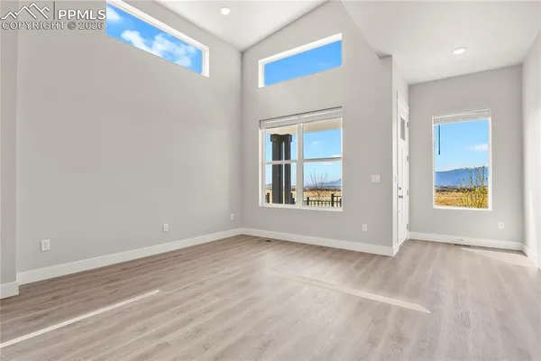 a view of an empty room with window and wooden floor