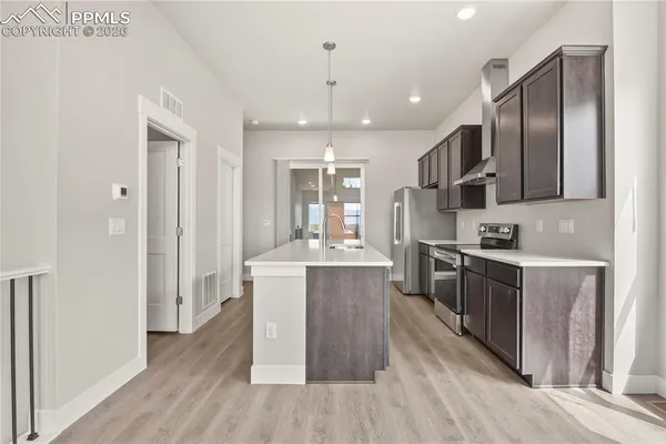 a large kitchen with stainless steel appliances lots of counter top space and wooden floor