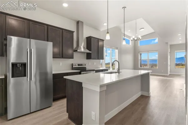 a kitchen with stainless steel appliances a sink a refrigerator a center island a stove and a view of living room