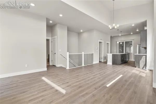 an empty room with wooden floor and kitchen view