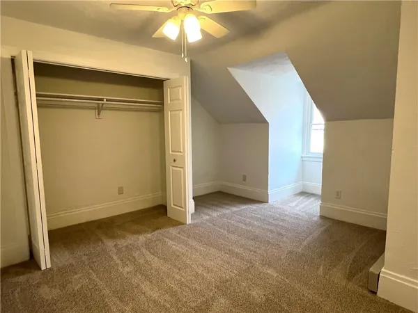 an empty room with a chandelier fan and closet