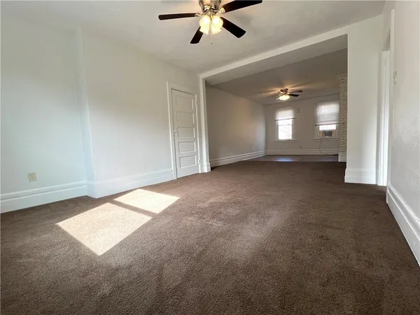 an empty room with windows and fan