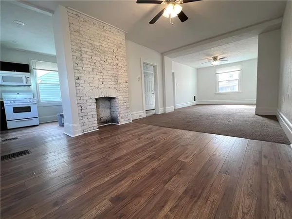 an empty room with wooden floor fireplace and windows