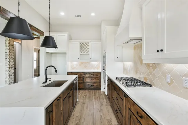 a kitchen with stainless steel appliances granite countertop a sink a stove and a wooden floors
