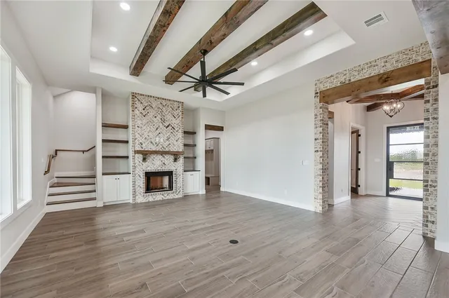 a view of a livingroom with a fireplace wooden floor and a ceiling fan