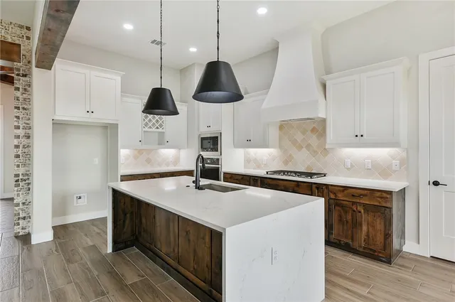 a kitchen with stainless steel appliances a sink a stove and a wooden floors