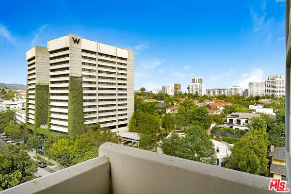 a view of a balcony with a couple of cars parked in front of a house