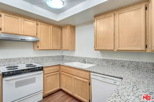 a kitchen with granite countertop white cabinets and white appliances
