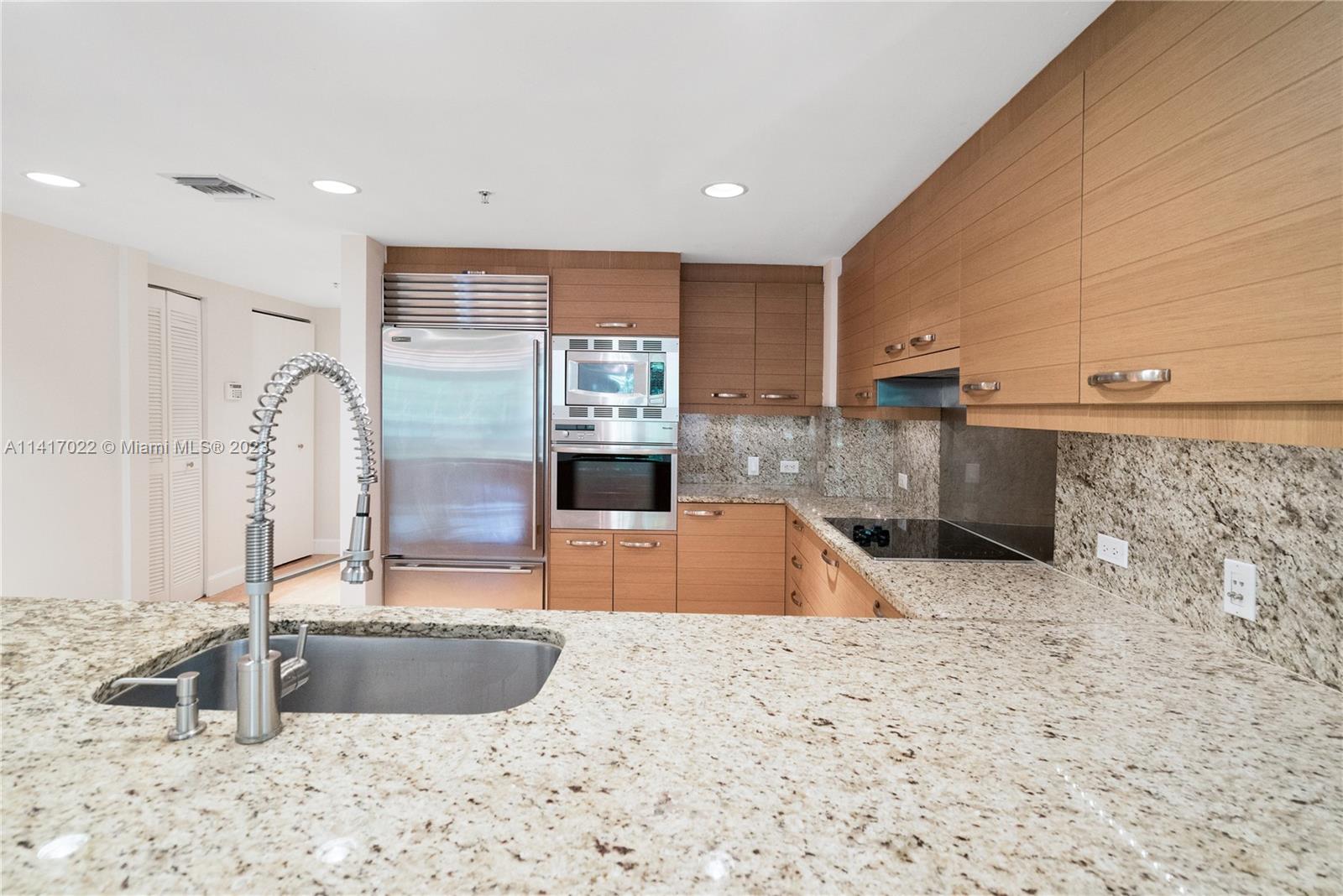 3540 Main Highway, Unit 309 Miami, FL 33133 - Photo 7 of 34 a large kitchen with kitchen island a sink a counter top and a stove