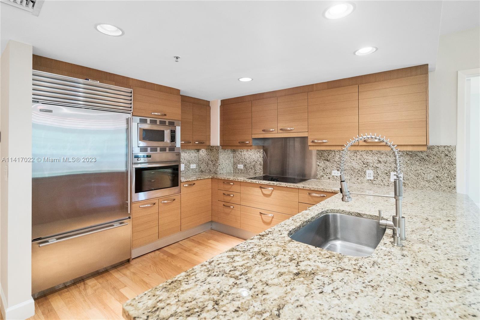 3540 Main Highway, Unit 309 Miami, FL 33133 - Photo 8 of 34 a kitchen with stainless steel appliances kitchen island granite countertop a sink and a stove