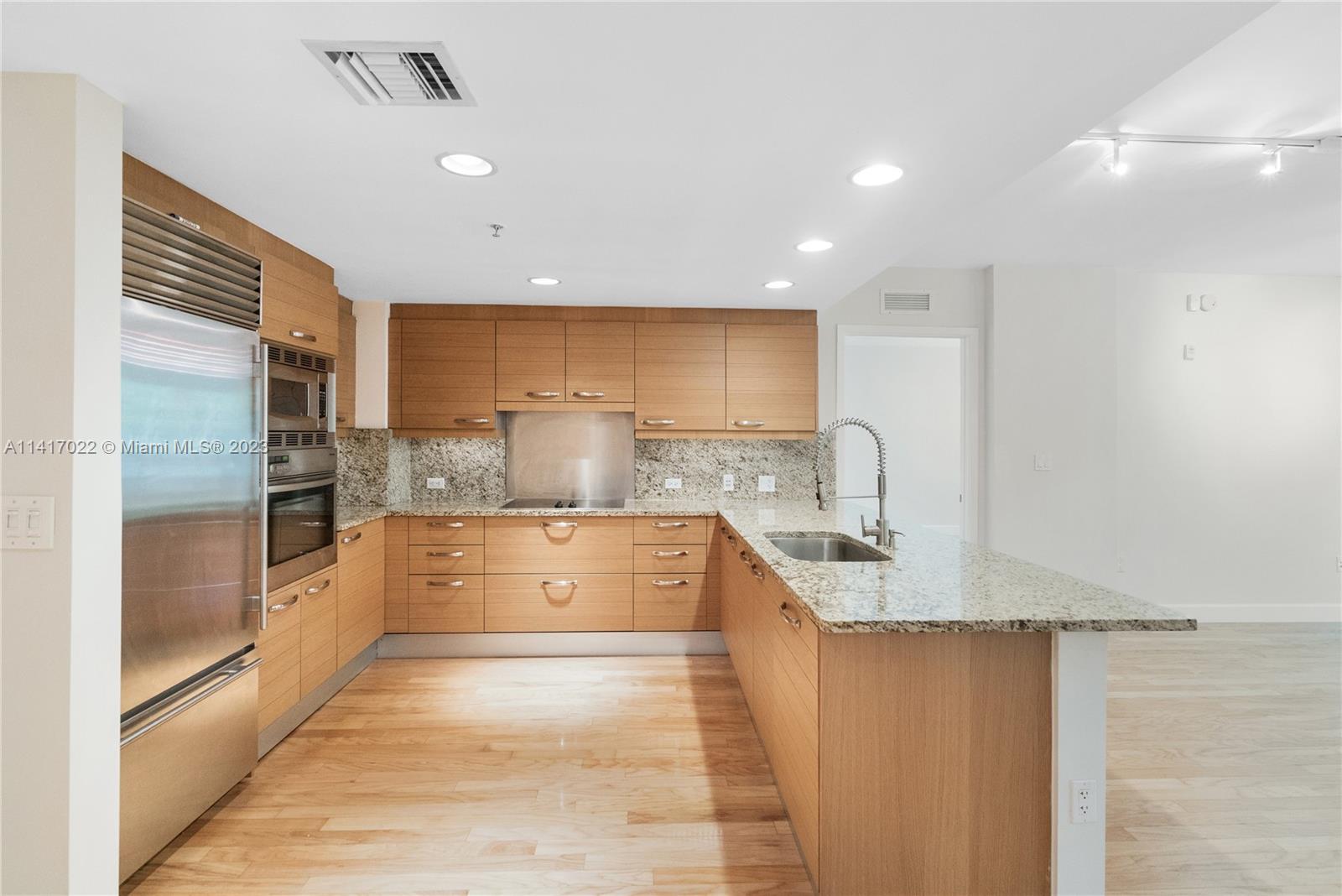 3540 Main Highway, Unit 309 Miami, FL 33133 - Photo 9 of 34 a large kitchen with granite countertop a large counter top stainless steel appliances and cabinets