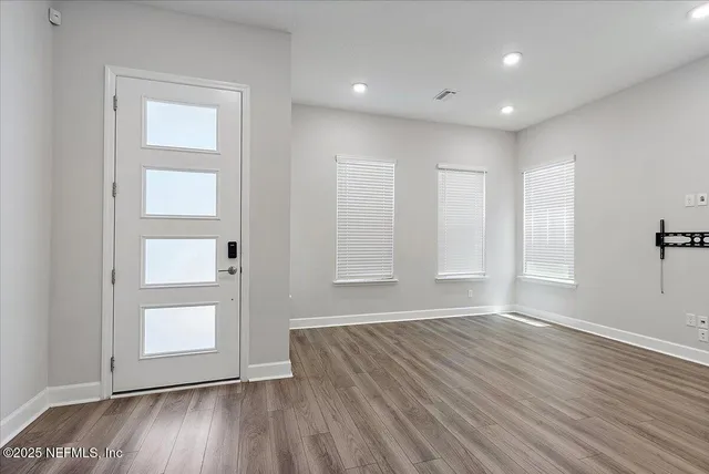 an empty room with wooden floor and windows