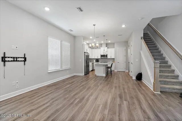 a view of a room with wooden floor stairs and a way to kitchen