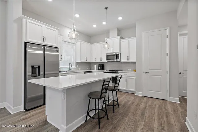 a kitchen with kitchen island a white counter space cabinets and stainless steel appliances
