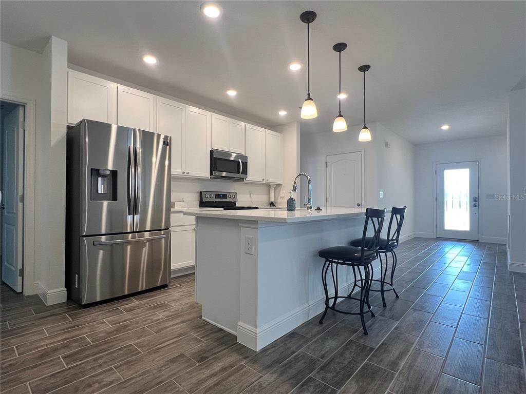 301 Jackson Loop DeLand, FL 32724 - Photo 6 of 22 a kitchen with kitchen island a refrigerator a stove a dining table and chairs with wooden floor