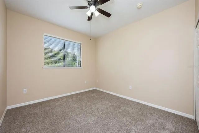 an empty room with a window and a fan