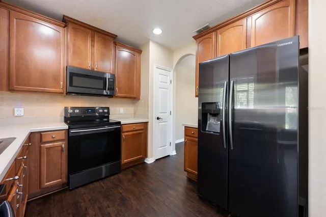a kitchen with stainless steel appliances granite countertop a refrigerator a stove a sink and a microwave
