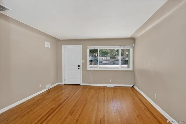 an empty room with wooden floor and windows