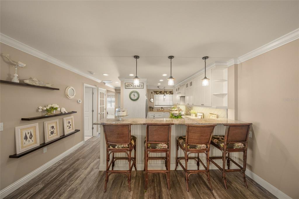 4660 Ocean Boulevard, Unit O2 Sarasota, FL 34242 - Photo 13 of 55 a kitchen with stainless steel appliances a dining table chairs and wooden floor