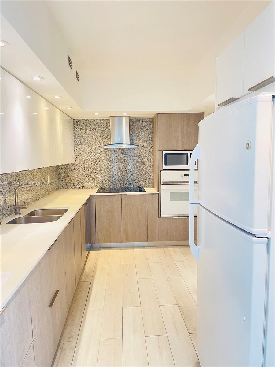 a large kitchen with a refrigerator sink and white cabinets
