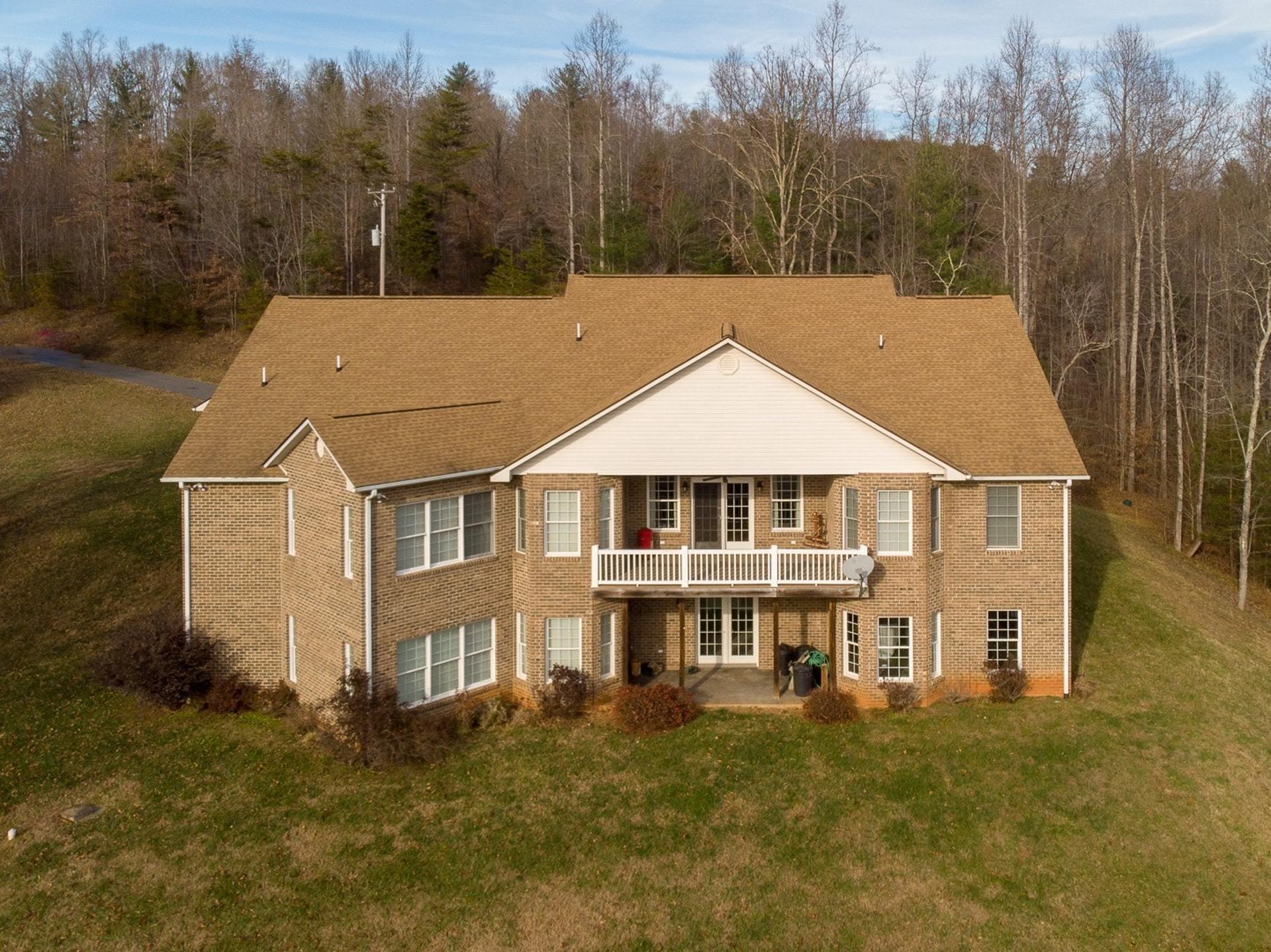 a aerial view of a white house with a big yard and large trees