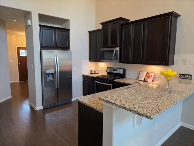 a kitchen with stainless steel appliances granite countertop a refrigerator a stove and a sink