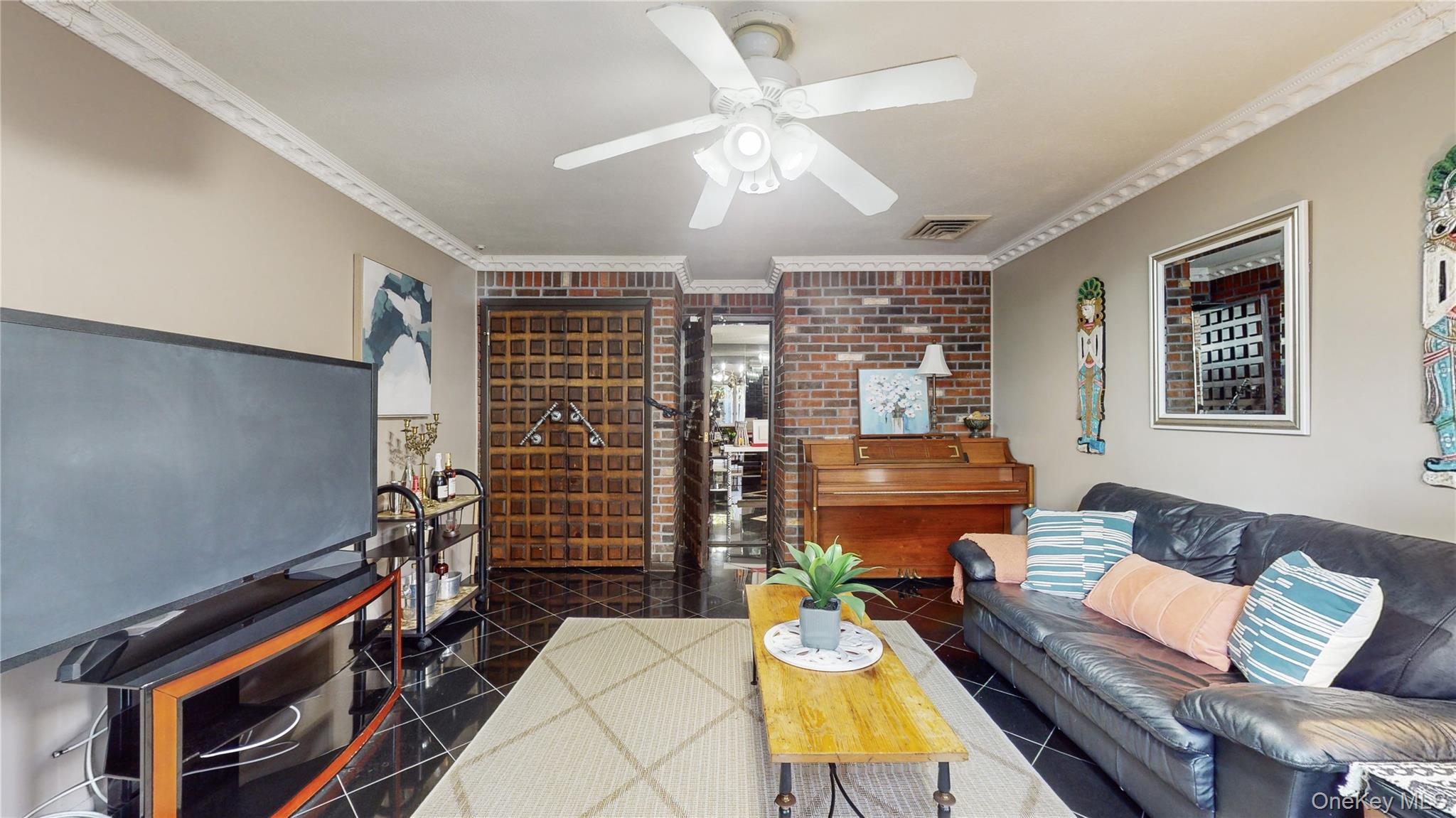 52-04 Redfield Street Queens, NY 11362 - Photo 19 of 25 Living area with crown molding, brick wall, and ceiling fan