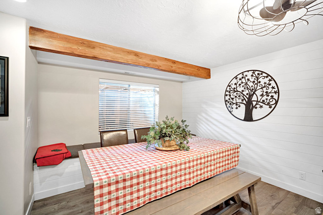 2139 Village Point Way Sandy, UT 84093 - Photo 24 of 35 Dining area featuring a prominent wood-finish beam, shiplap accent wall, built-in bench seating with storage underneath, wood-finish flooring.