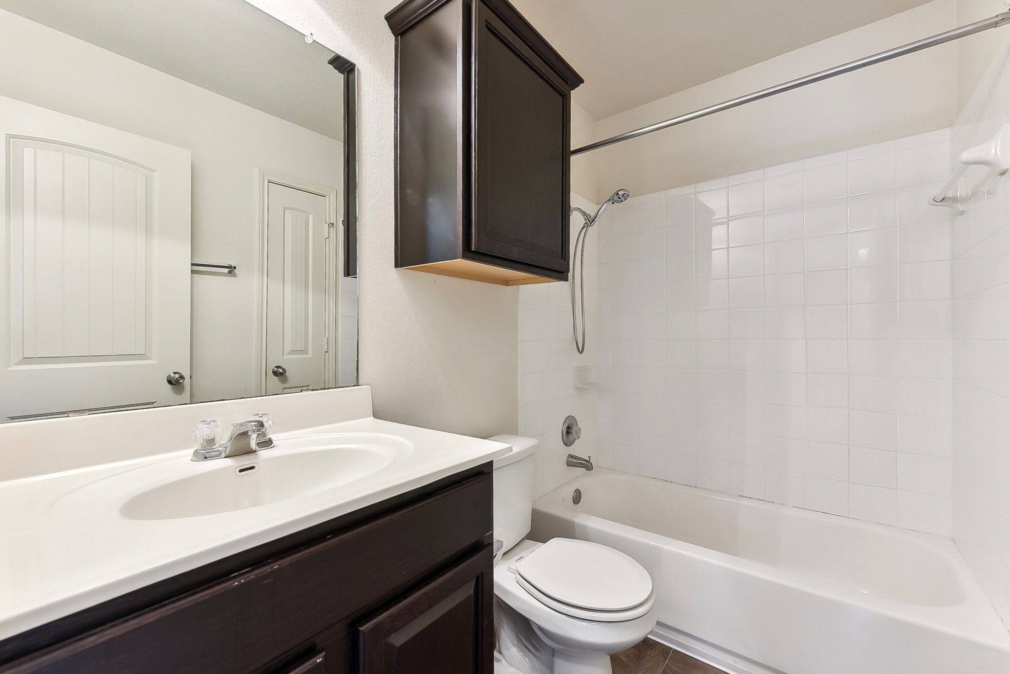 310 Potters Peak Way Georgetown, TX 78626 - Photo 11 of 21 Bathroom featuring a white integrated sink and countertop, dark wood-finish vanity, wall-mounted mirror, white subway tile shower surround, and a white bathtub with shower kit