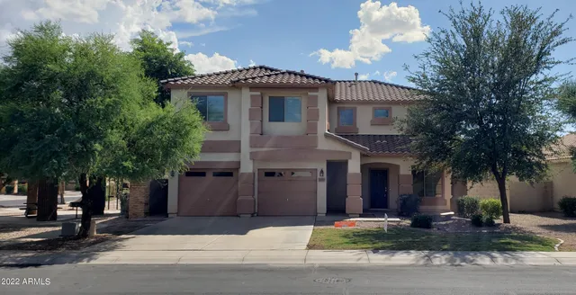 a front view of a house with garden and trees