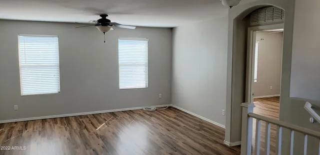 a view of empty room with wooden floor and fan
