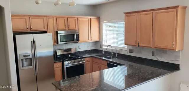 a kitchen with granite countertop a sink a counter top space stainless steel appliances and cabinets