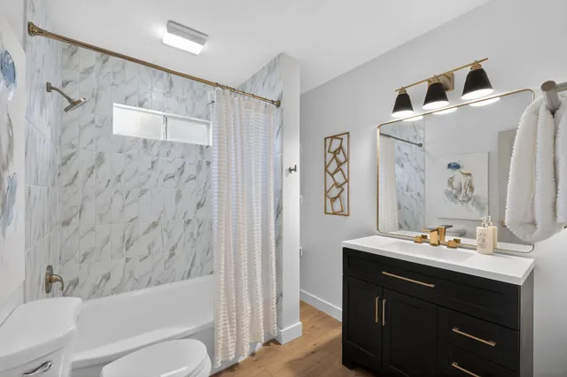 a bathroom with a bathtub sink vanity mirror and toilet