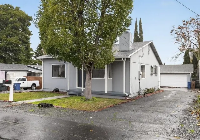 a view of a house with a yard and large tree