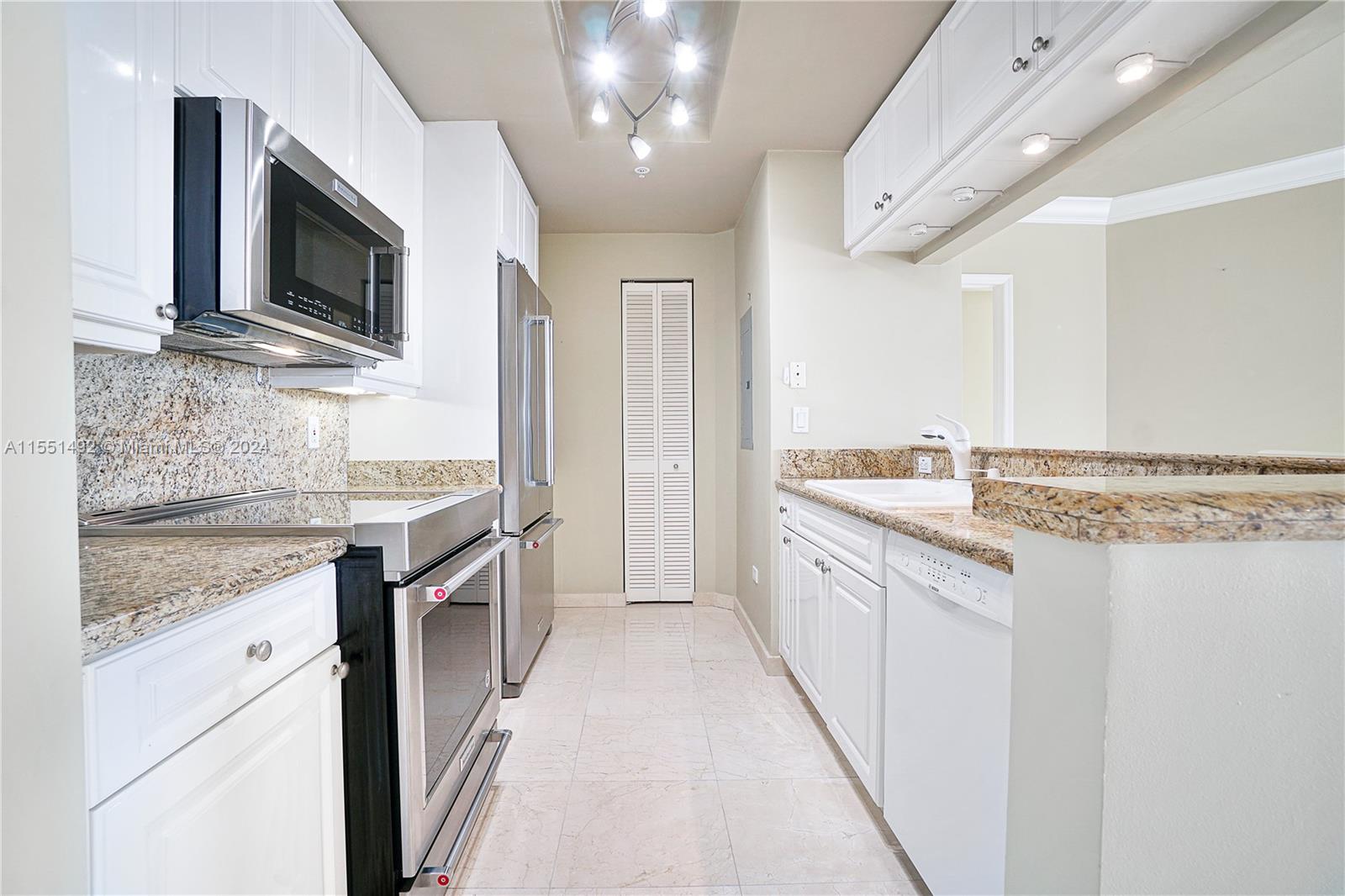 848 Brickell Key Drive, Unit 2003 Miami, FL 33131 - Photo 11 of 35 a large kitchen with granite countertop a sink and a stove top oven