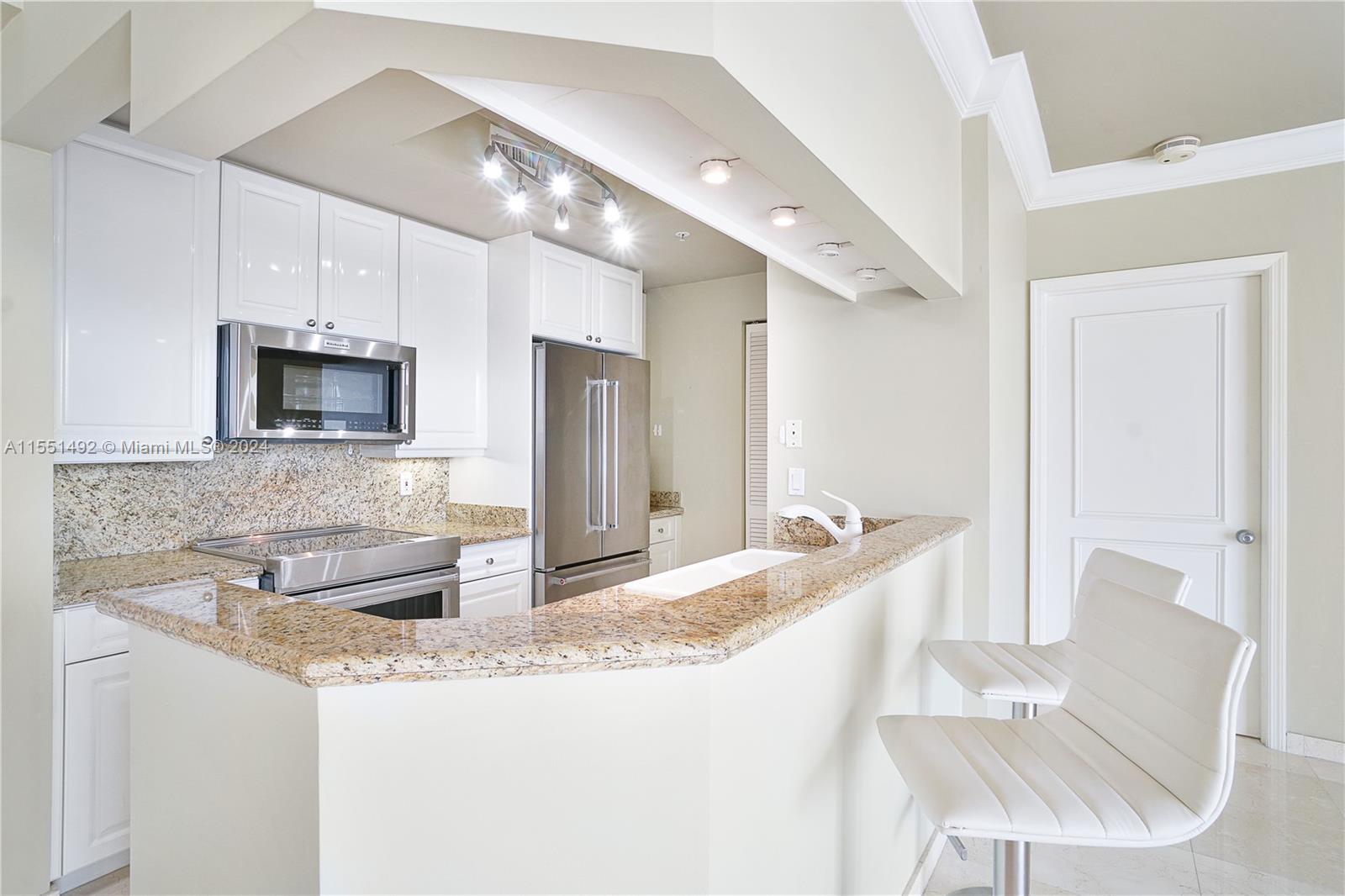 848 Brickell Key Drive, Unit 2003 Miami, FL 33131 - Photo 27 of 35 a large kitchen with granite countertop a sink and a refrigerator