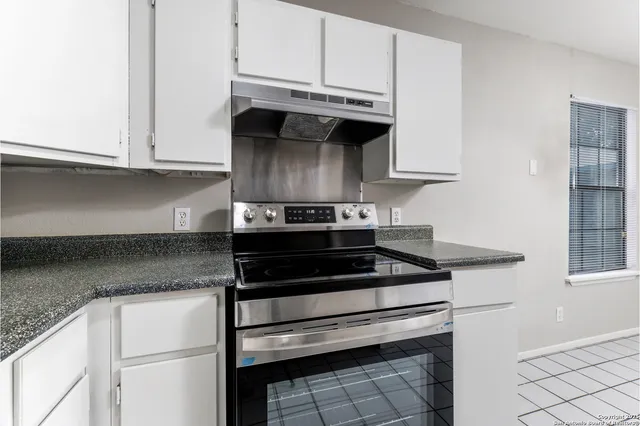 a kitchen with granite countertop white cabinets and appliances