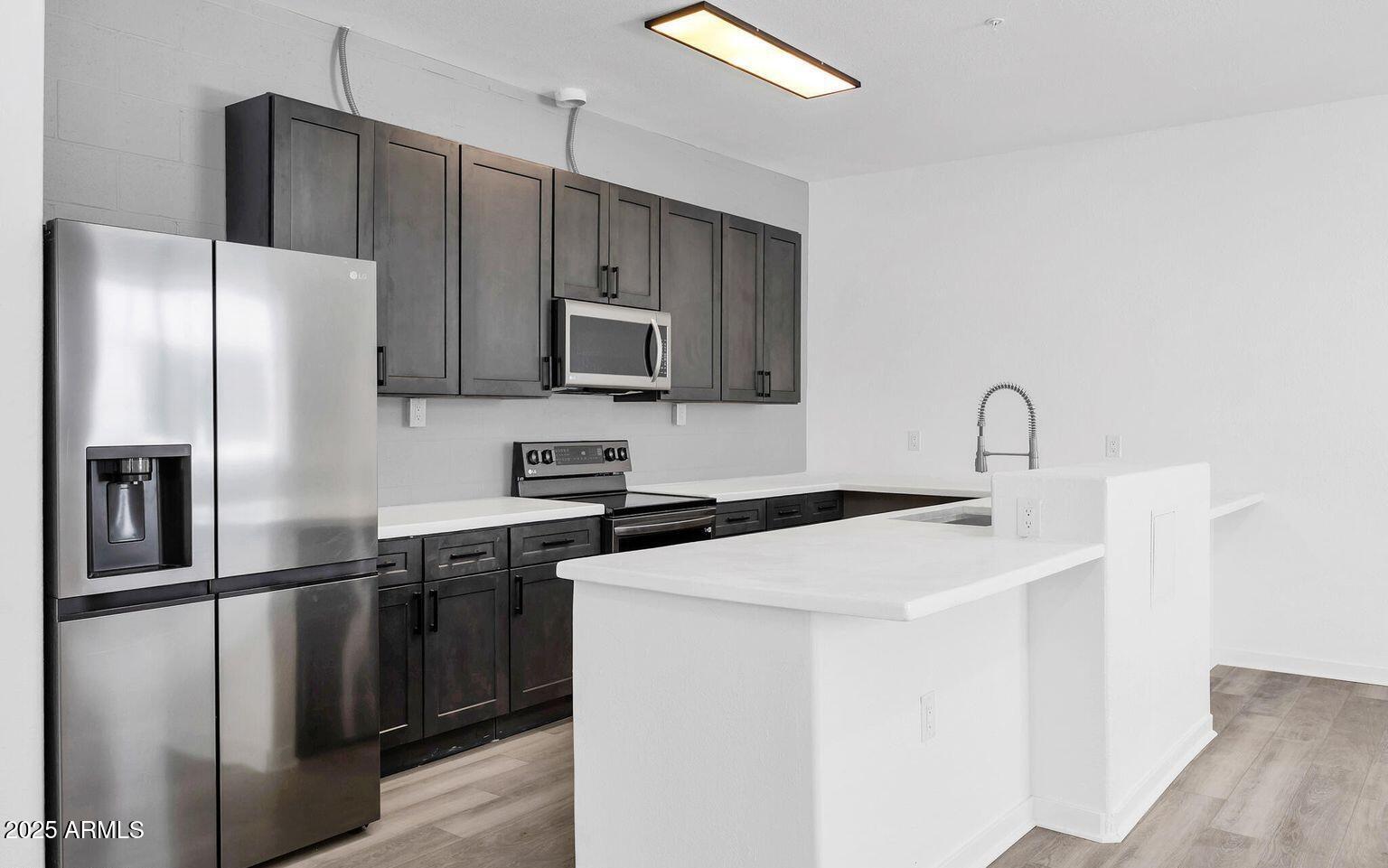 a kitchen with stainless steel appliances a refrigerator sink and microwave